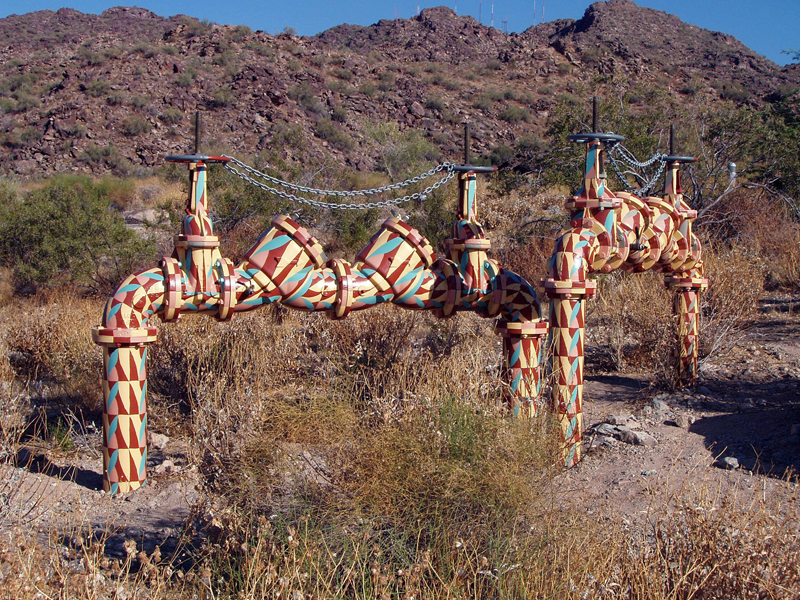 Photograph of Naturalized Infrastructure, a set of backflow devices painted with an unusual desert camouflage to match the natural color scheme