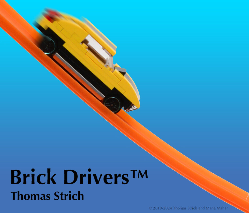 Brick Drivers Thomas Strich. A yellow car made of toy bricks on a metal base rolls down an orange toy race car track. 